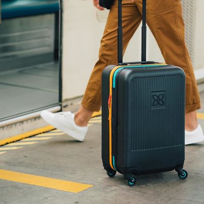 Устойчивый чемодан с антиразбивающей внешней сетчатой компрессионной панелью и компрессионным ремнем, предназначенным для беззаботного передвижения